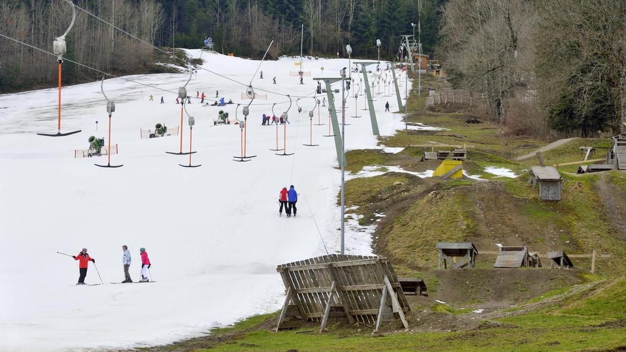 Skifahrer bei wenig Schnee am Streidlhang am Fuße des Brauneck bei Bad Tölz. Skifahrer bei wenig Schnee am Streidlhang am Fuße des Brauneck bei Bad Tölz.