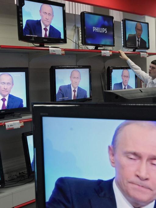 Wladimir Putin ist in einem Geschäft auf diversen TV-Bildschirmen zu sehen.