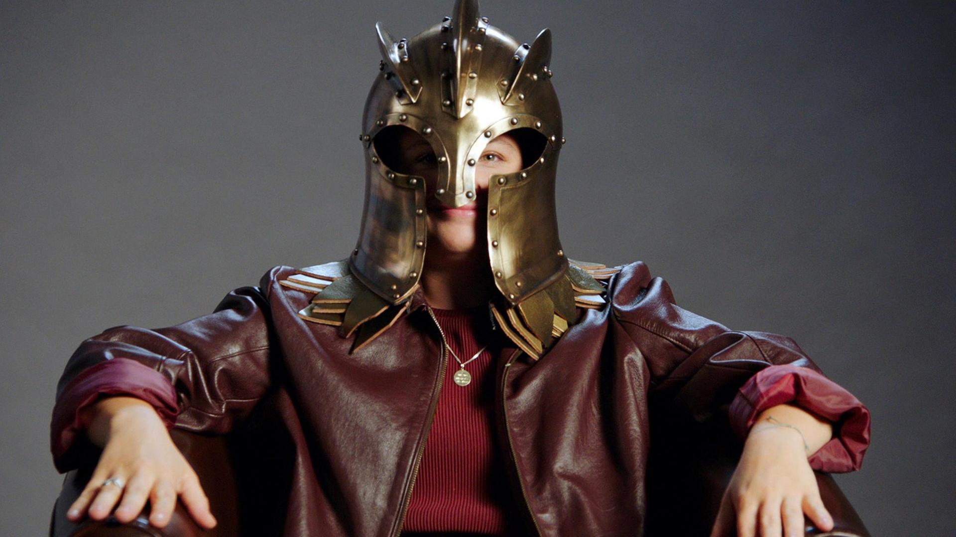 Eine Frau sitzt auf einem Stuhl und trägt eine Maske aus der Serie "Games of Thrones". Eine Frau sitzt auf einem Stuhl und trägt eine Maske aus der Serie "Games of Thrones".