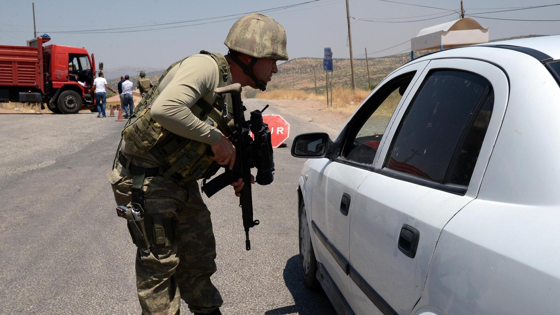 An einem Kontrollpunkt der türkischen Armee in Diyabakir an der Grenze zu Syrien überprüft ein Soldat mit Maschinengewehr einen Autofahrer. An einem Kontrollpunkt der türkischen Armee in Diyabakir an der Grenze zu Syrien überprüft ein Soldat mit Maschinengewehr einen Autofahrer.