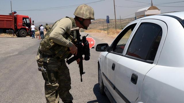 An einem Kontrollpunkt der türkischen Armee in Diyabakir an der Grenze zu Syrien überprüft ein Soldat mit Maschinengewehr einen Autofahrer.