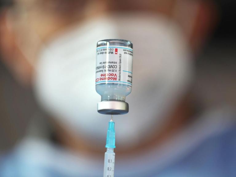 Ein Arzt zieht eine Spritze mit dem Impfstoff von Moderna auf
