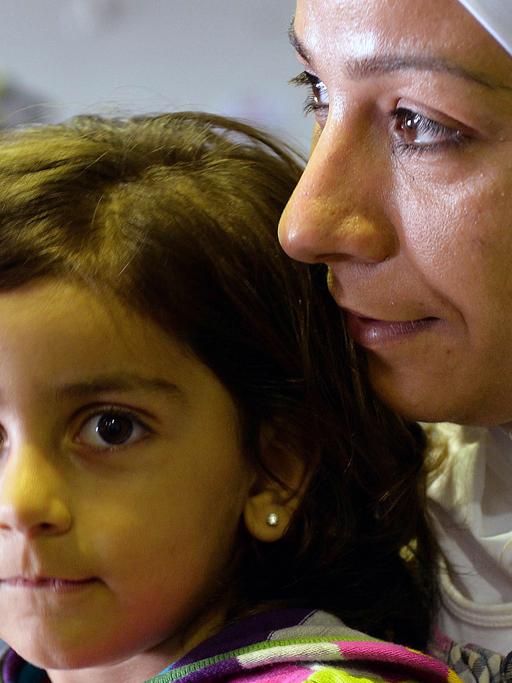 Eine Frau mit Kopftuch mit Kind auf dem Schoß - sie gehörten zur ersten syrischen Flüchtlingsgruppe, die im September 2013 in Hannover gelandet ist.