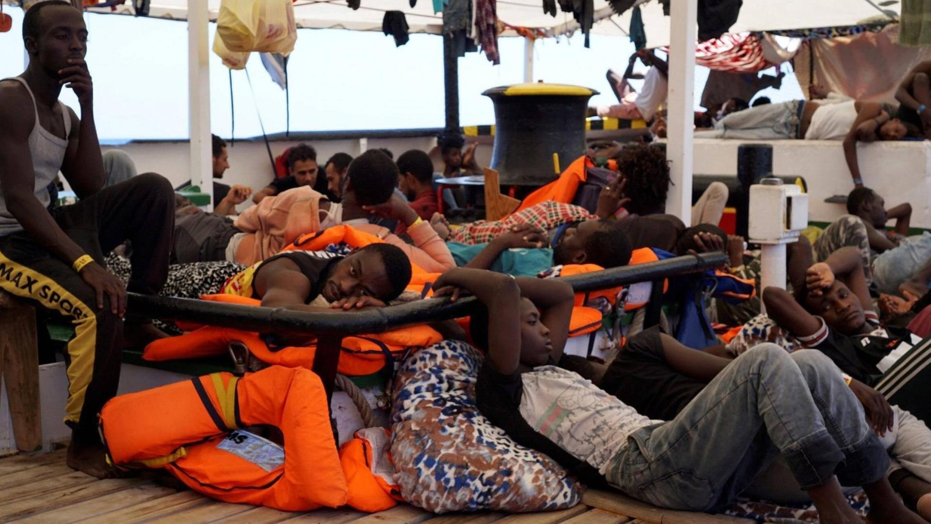 Das Bild zeigt Flüchtlinge an Bord des Rettungsschiffs "Open Arms", die auf Deck ausharren. Das Bild zeigt Flüchtlinge an Bord des Rettungsschiffs "Open Arms", die auf Deck ausharren.