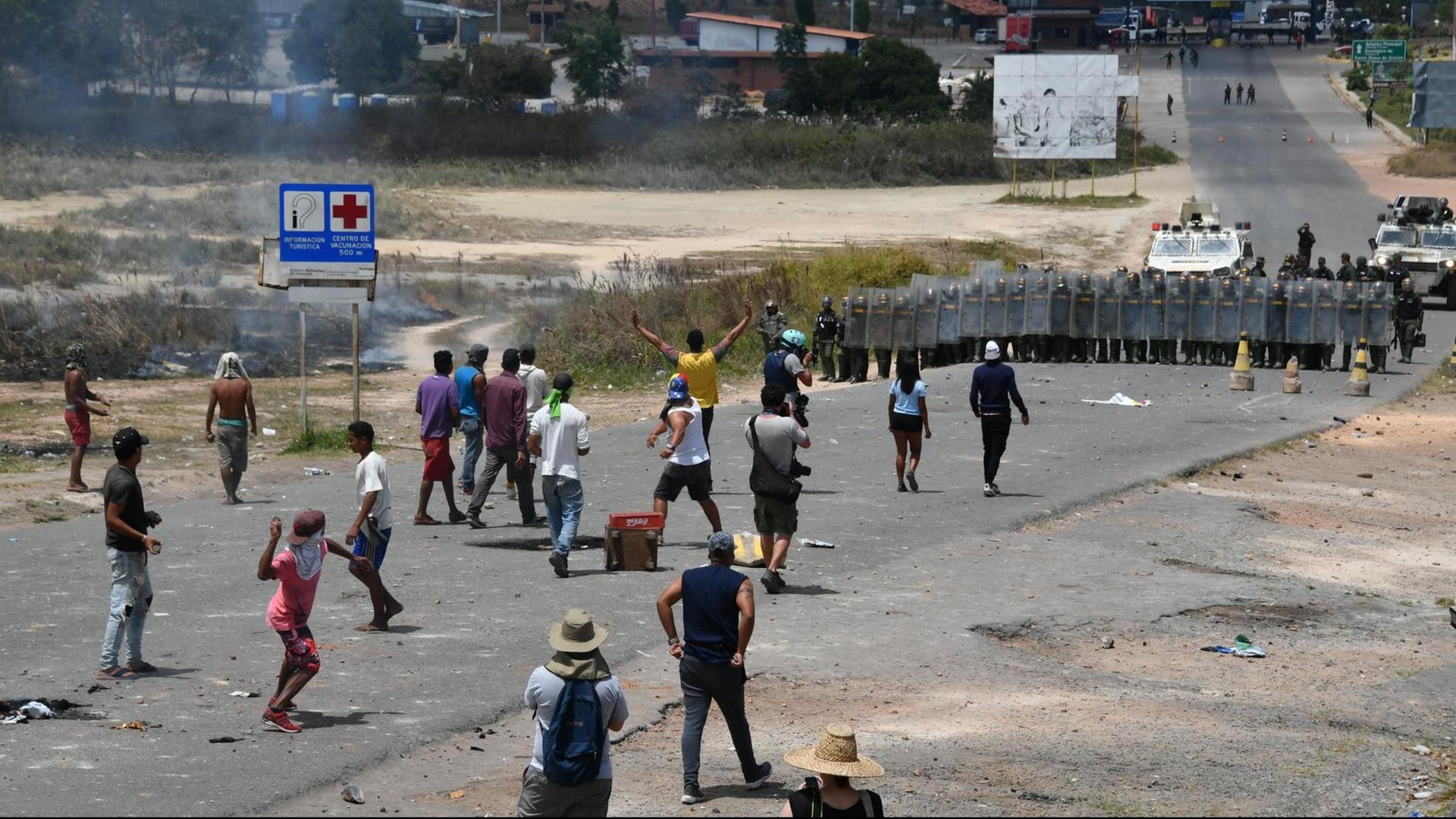 Demonstranten werfen Steine auf Mitglieder der venezolanischen Nationalgarde, die die Grenze von Venezuela zu Brasilien bewachen. Demonstranten werfen Steine auf Mitglieder der venezolanischen Nationalgarde, die die Grenze von Venezuela zu Brasilien bewachen.