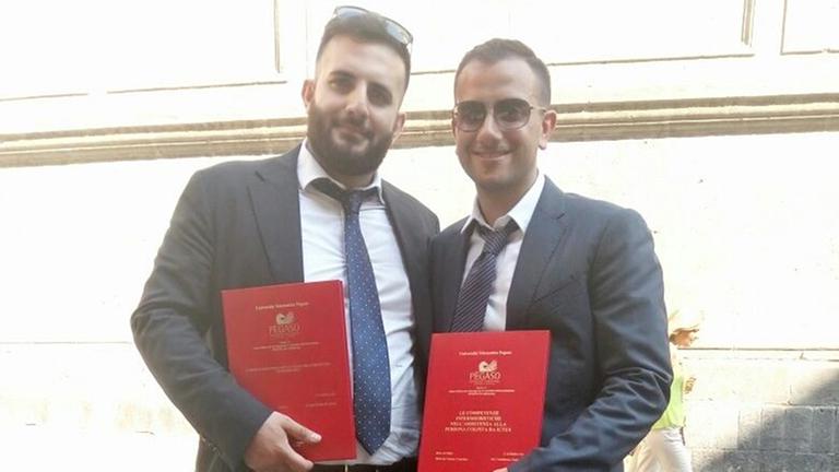 Busunternehmer Raffaele Di Sieno und Krankenpfleger Umberto Formisano stehen in Anzug auf der Straße. Busunternehmer Raffaele Di Sieno und Krankenpfleger Umberto Formisano stehen in Anzug auf der Straße.