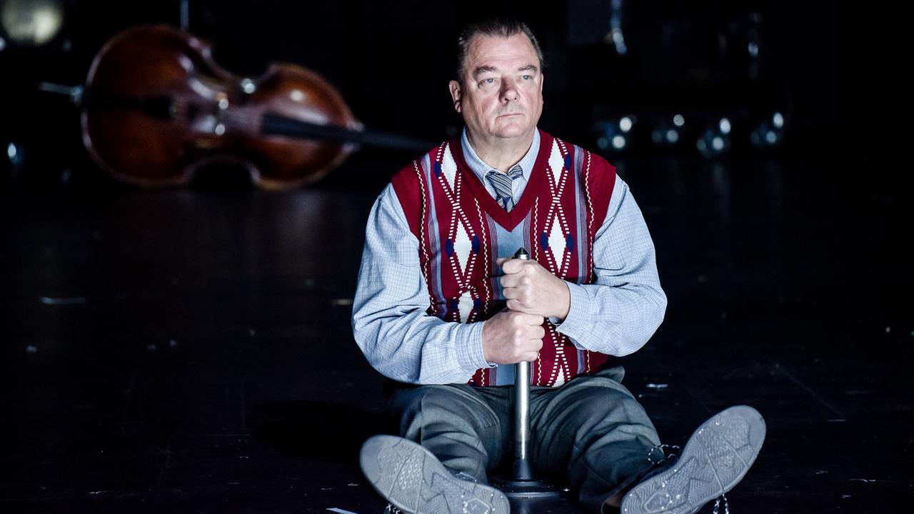 Das Bild zeigt den Schauspieler Peter Kurth, sitzend auf der Bühne, in dem Stück "Die stillen Trabanten" von Clemens Meyer.