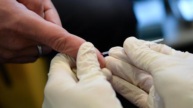 Ein Arzt nimmt am 15.11.2016 in Berlin bei der Berliner Aids-Hilfe e.v. an dem Finger eines jungen Mannes Blut ab.
