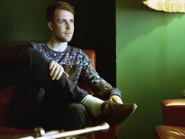 Paul Hübner sitzt auf Sofa vor seiner Trompete
