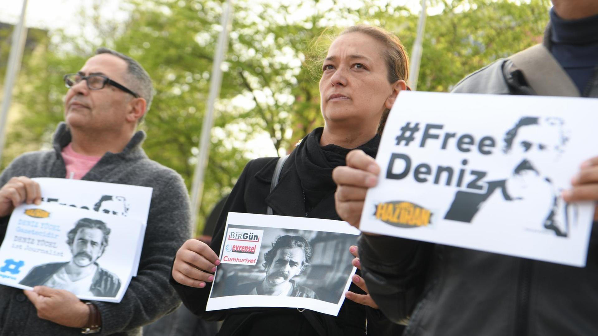 Teilnehmer einer Mahnwache halten am 13.04.2017 vor der Stadthalle in Flörsheim (Hessen) Schilder mit der Aufschrift "#FreeDeniz" und dem Porträt des in der Türkei inhaftierten deutsch-türkischen Journalisten Deniz Yücel in den Händen. Der aus Flörsheim stammende Türkei-Korrespondent der Zeitung «Die Welt» wurde Mitte Februar in Istanbul festgenommen. Seit Anfang März sitzt er unter dem Verdacht der Terrorpropaganda in Haft. Foto: Arne Dedert/dpa | Verwendung weltweit Teilnehmer einer Mahnwache halten am 13.04.2017 vor der Stadthalle in Flörsheim (Hessen) Schilder mit der Aufschrift "#FreeDeniz" und dem Porträt des in der Türkei inhaftierten deutsch-türkischen Journalisten Deniz Yücel in den Händen. Der aus Flörsheim stammende Türkei-Korrespondent der Zeitung «Die Welt» wurde Mitte Februar in Istanbul festgenommen. Seit Anfang März sitzt er unter dem Verdacht der Terrorpropaganda in Haft. Foto: Arne Dedert/dpa | Verwendung weltweit