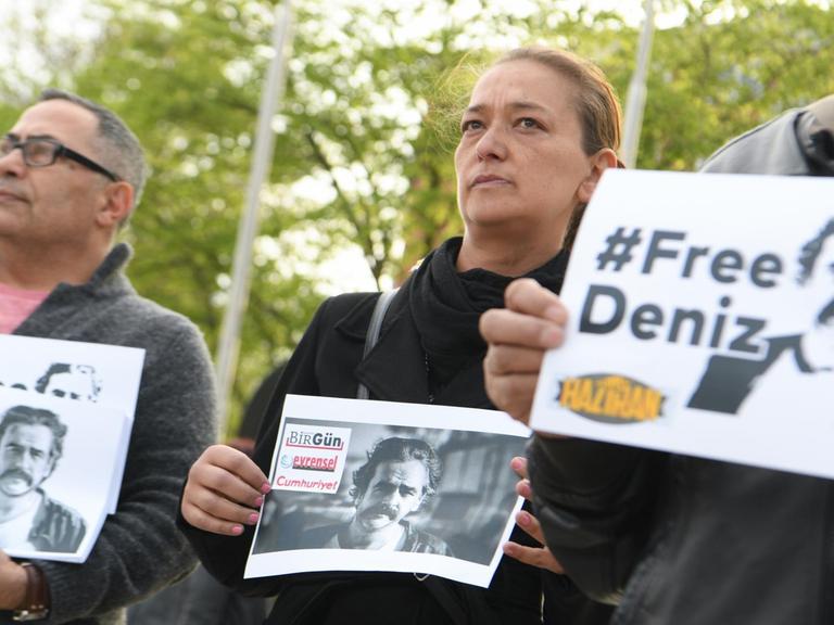 Teilnehmer einer Mahnwache halten am 13.04.2017 vor der Stadthalle in Flörsheim (Hessen) Schilder mit der Aufschrift "#FreeDeniz" und dem Porträt des in der Türkei inhaftierten deutsch-türkischen Journalisten Deniz Yücel in den Händen. Der aus Flörsheim stammende Türkei-Korrespondent der Zeitung «Die Welt» wurde Mitte Februar in Istanbul festgenommen. Seit Anfang März sitzt er unter dem Verdacht der Terrorpropaganda in Haft. Foto: Arne Dedert/dpa | Verwendung weltweit