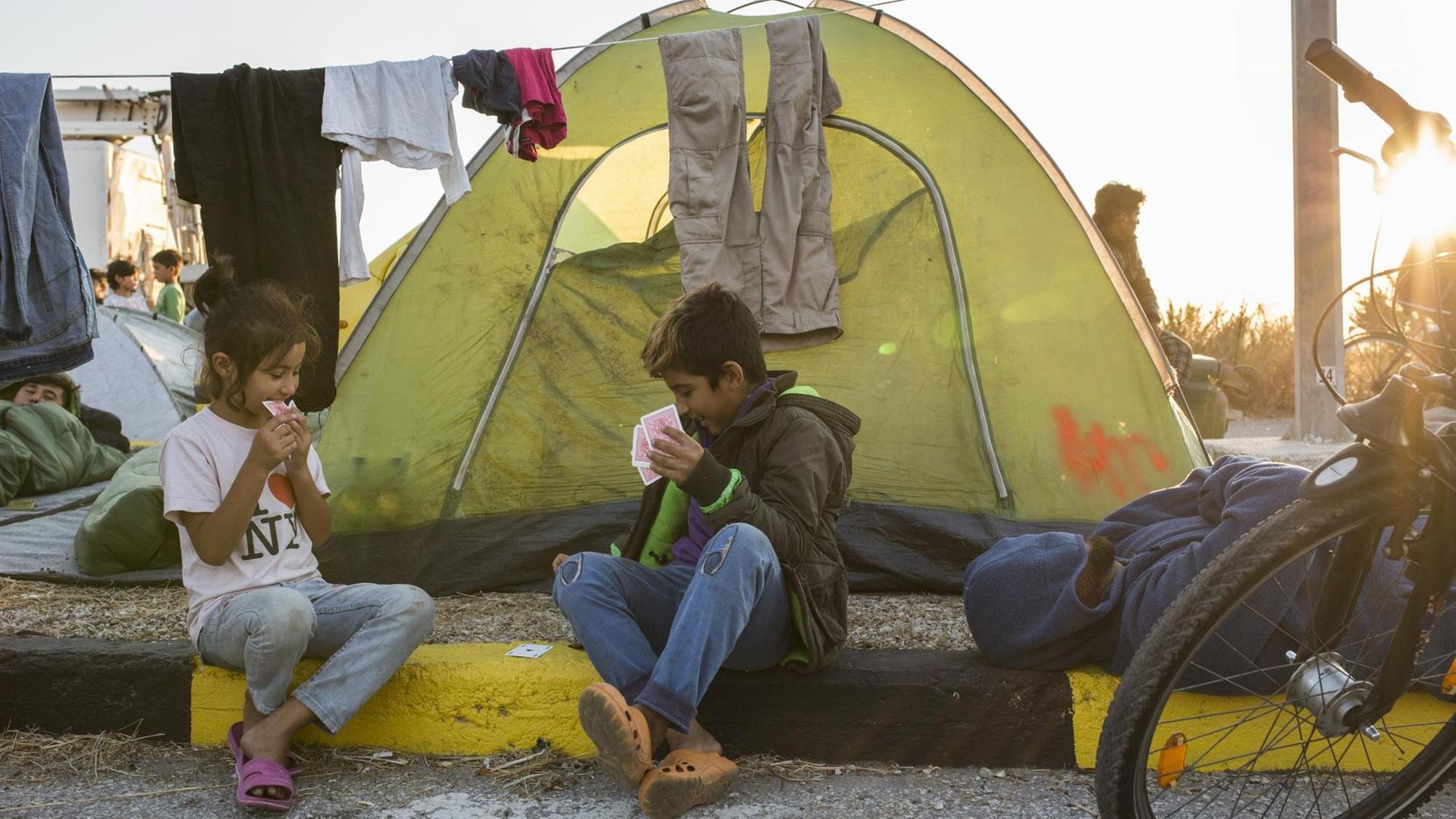 Kinder spielen Karten am Straßenrand in der Nähe des ausgebrannten Flüchtlingslagers Moria Kinder spielen Karten am Straßenrand in der Nähe des ausgebrannten Flüchtlingslagers Moria