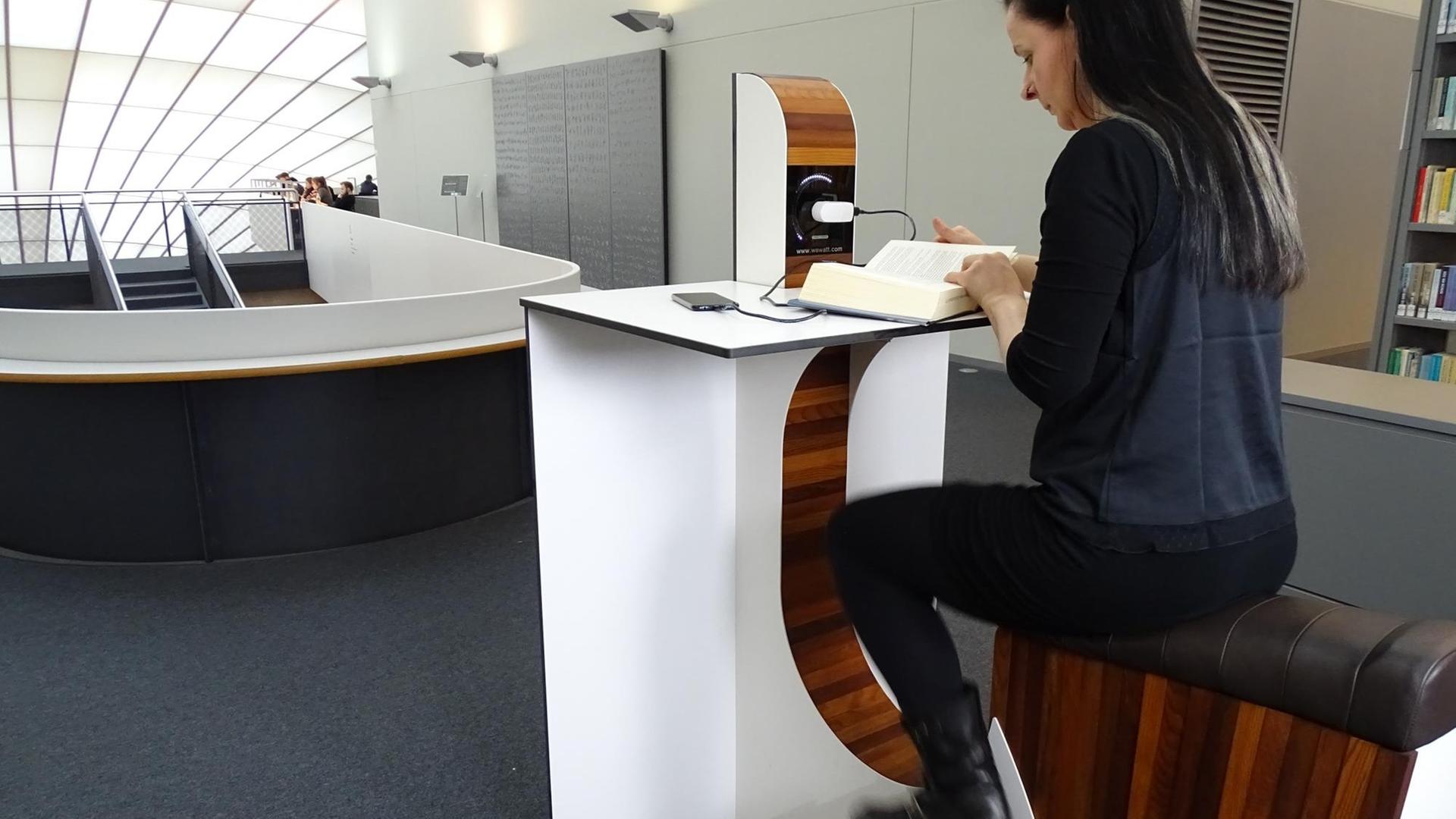 Eine Frau sitzt auf dem Fahrradergometer in der Philologischen Bibliothek der FU Berlin. Eine Frau sitzt auf dem Fahrradergometer in der Philologischen Bibliothek der FU Berlin.