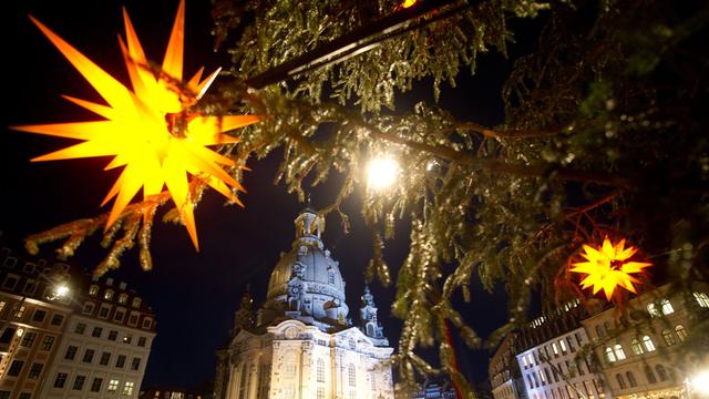 Tausende Menschen stehen abends auf dem hell erleuchteten Platz vor der Dresdner Frauenkirche.