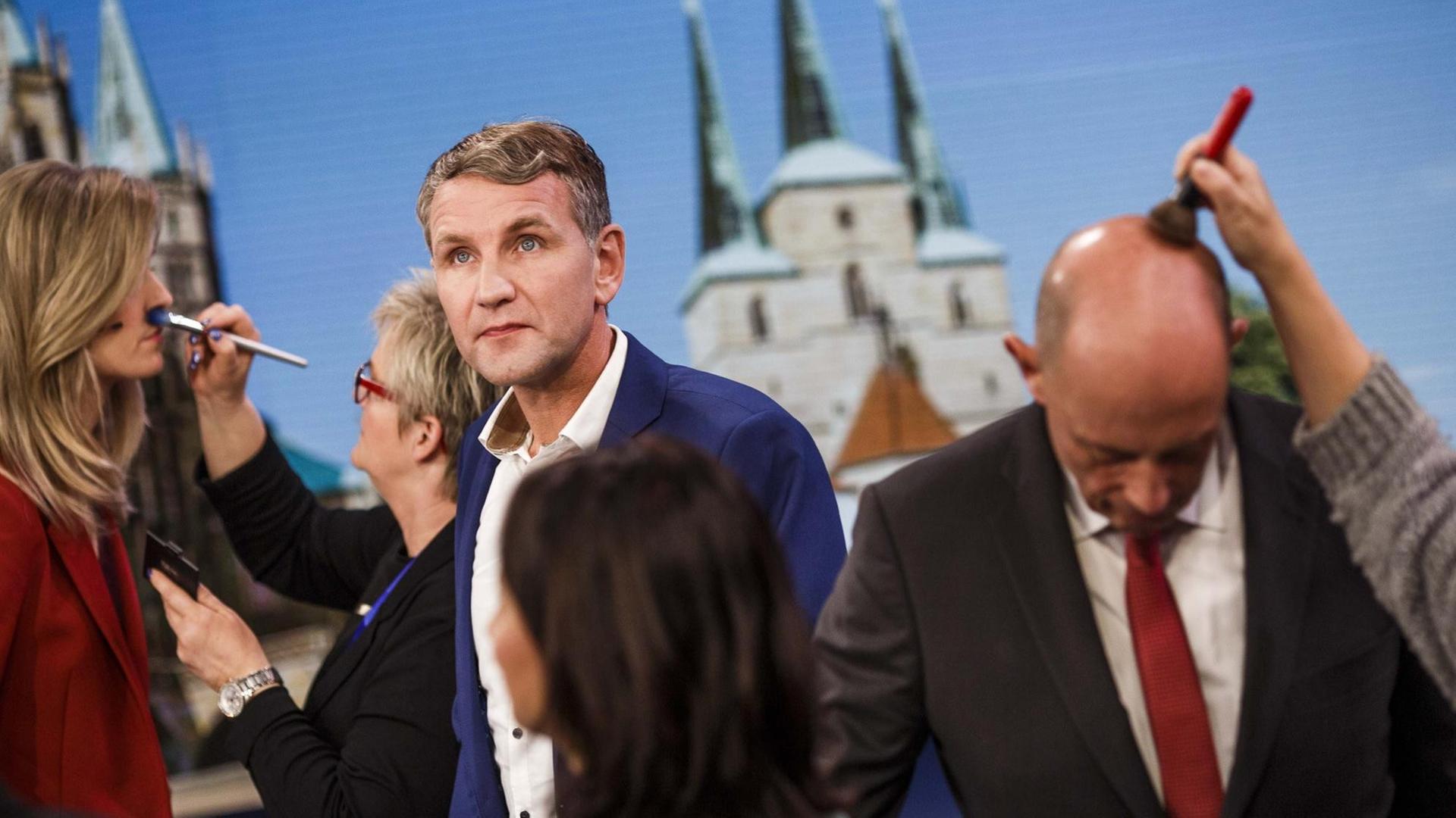 Björn Höcke von der rechten Alternative für Deutschland (AfD) kommt nach der Landtagswahl in Thüringen am 27. Oktober 2019 in Erfurt zu einem Fernsehinterview ins Studio, während weitere Gäste bereits von der Maske abgepinselt werden. Björn Höcke von der rechten Alternative für Deutschland (AfD) kommt nach der Landtagswahl in Thüringen am 27. Oktober 2019 in Erfurt zu einem Fernsehinterview ins Studio, während weitere Gäste bereits von der Maske abgepinselt werden.