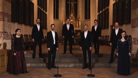 Acht Sänger und Sängerinnen stehen auf den Altarstufen einer Kirche.