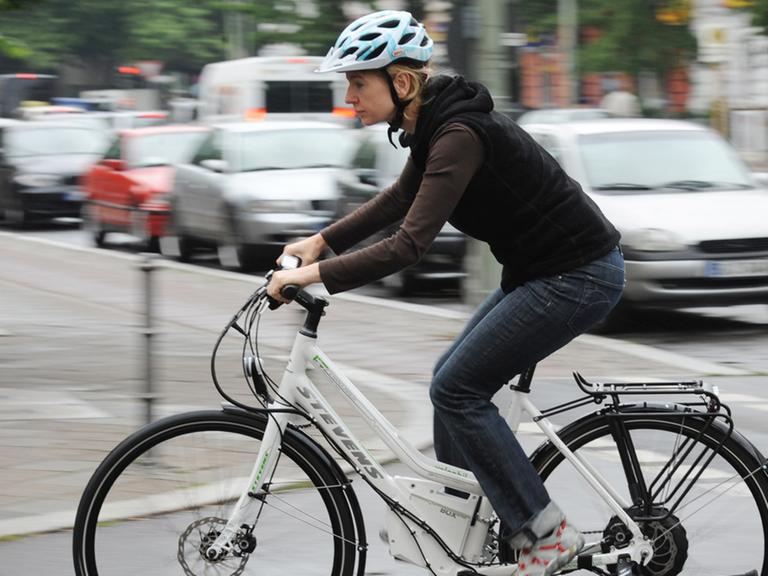 Eine Frau bewegt ein Elektrofahrrad durch Berlin. Die Deutschen nutzen zum Beispiel auf dem Weg zur Arbeit immer häufiger Elektrofahrräder.