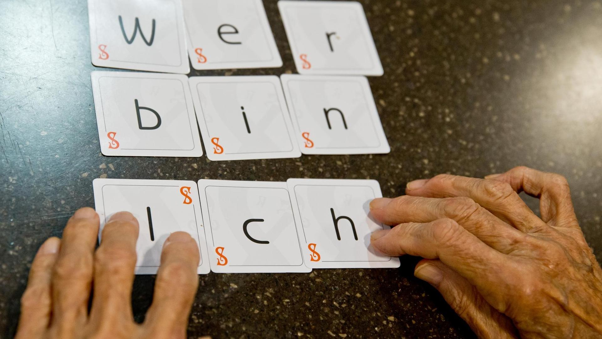 Eine Demenzkranke Frau legt die Karten eines Spiels zu dem Satz "wer bin ich" zusammen. Eine Demenzkranke Frau legt die Karten eines Spiels zu dem Satz "wer bin ich" zusammen.