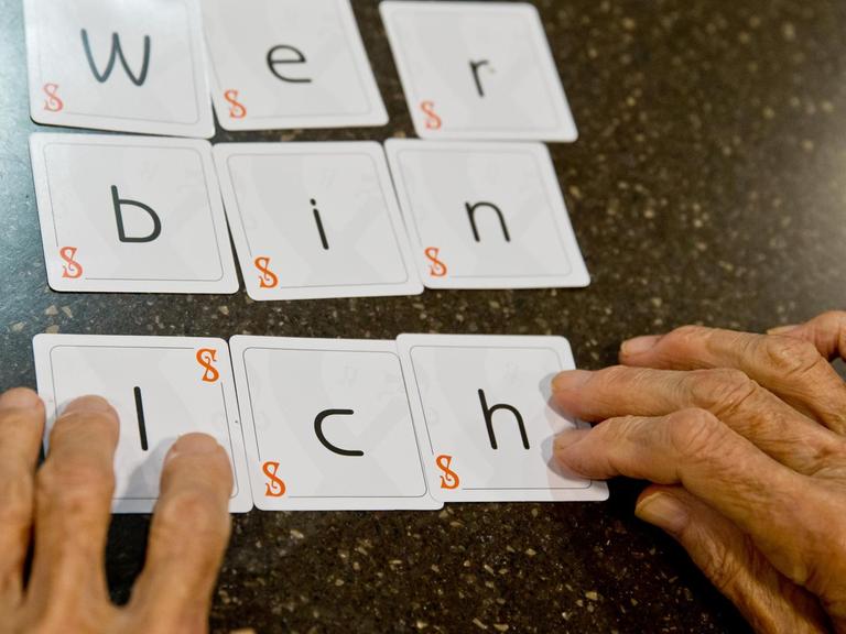 Eine Demenzkranke Frau legt die Karten eines Spiels zu dem Satz "wer bin ich" zusammen.