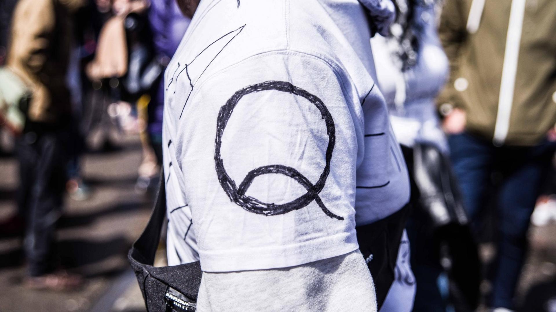 Eine Person trägt auf dem Ärmel ihres Shirts das Logo von QAnon.