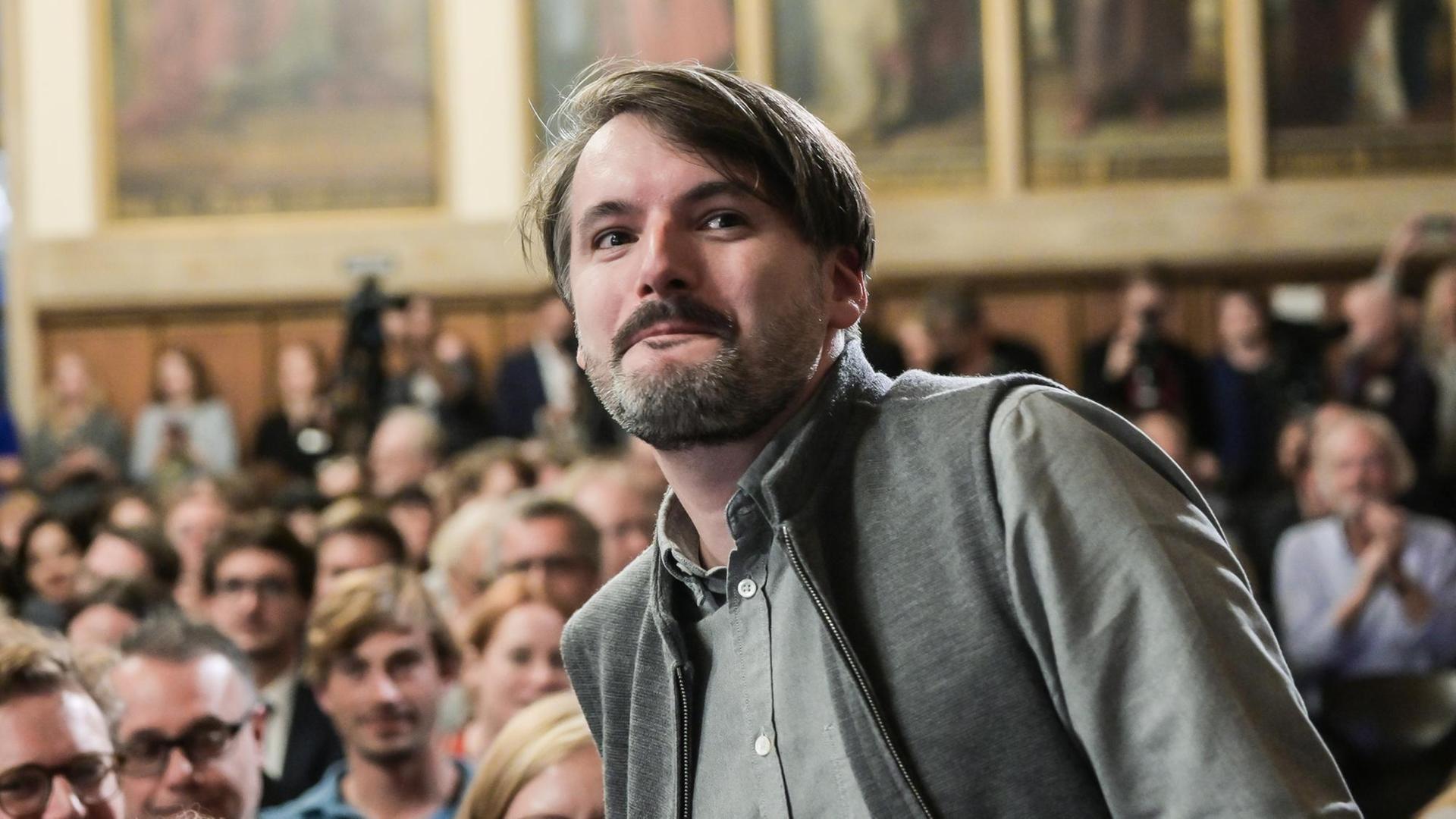 Der Schriftsteller Saša Stanišić erhebt sich, um den Deutschen Buchpreis entgegen zu nehmen Der Schriftsteller Saša Stanišić erhebt sich, um den Deutschen Buchpreis entgegen zu nehmen