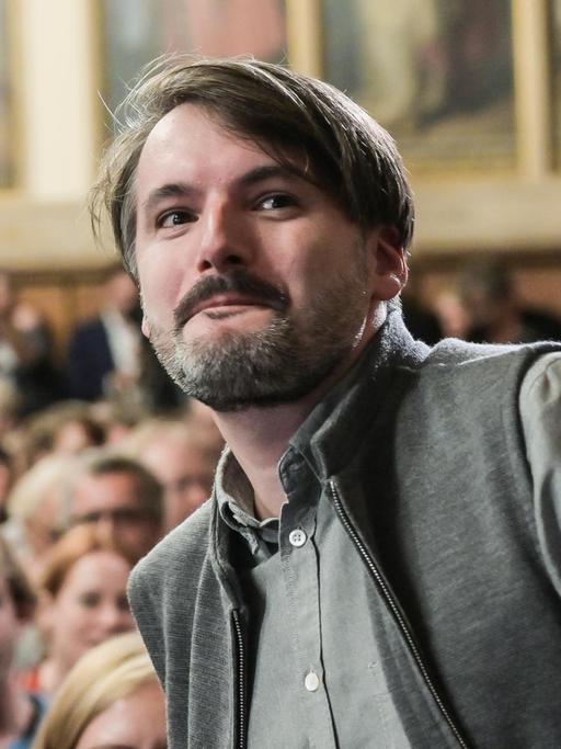 Der Schriftsteller Saša Stanišić erhebt sich, um den Deutschen Buchpreis entgegen zu nehmen