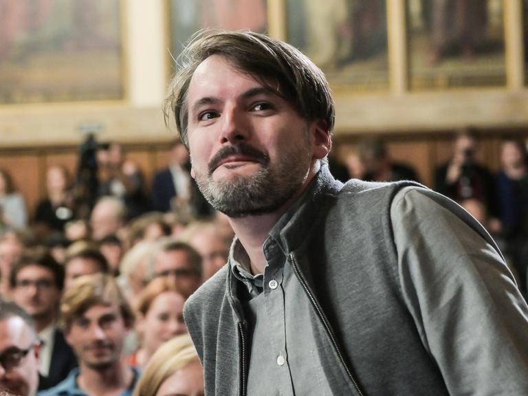 Der Schriftsteller Saša Stanišić erhebt sich, um den Deutschen Buchpreis entgegen zu nehmen