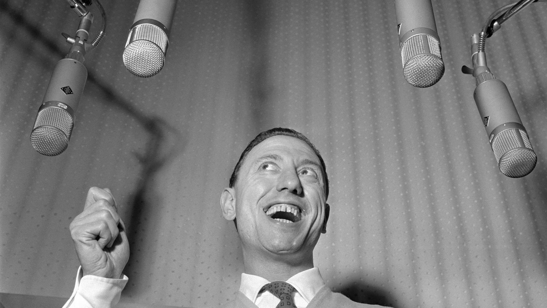 Ein schwarz weiss Portrait vom italienischen Sänger und Entertainer Renato Carosone, umringt von vier Mikrofonen. Ein schwarz weiss Portrait vom italienischen Sänger und Entertainer Renato Carosone, umringt von vier Mikrofonen.