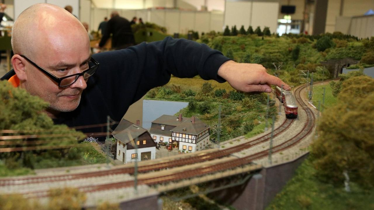 Mann an einer Modellbahn-Strecke auf der Messe in München Mann an einer Modellbahn-Strecke auf der Messe in München