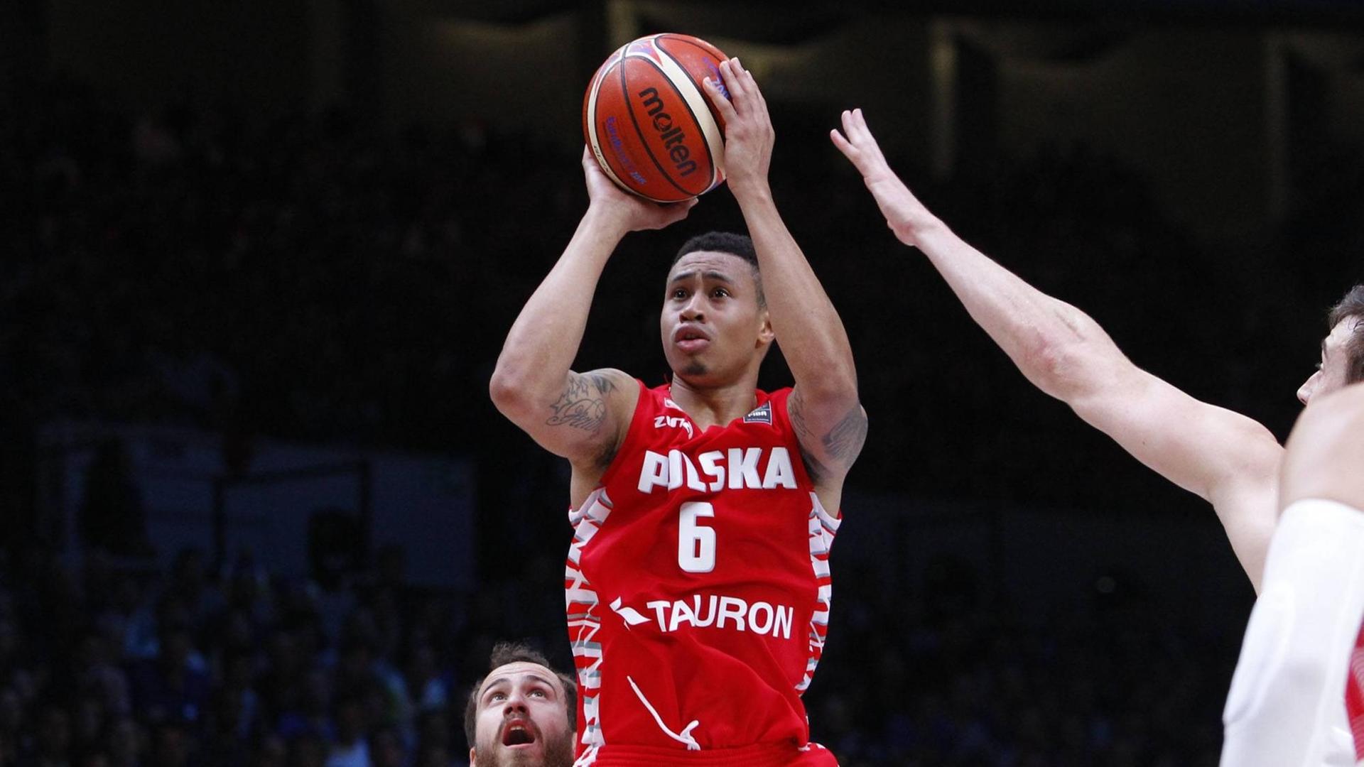 Der US-amerikanisch-polnische Basketballer AJ Slaughter im Nationaltrikot von Polen währende eines Spiels mit dem Ball in der Hand. Der US-amerikanisch-polnische Basketballer AJ Slaughter im Nationaltrikot von Polen währende eines Spiels mit dem Ball in der Hand.