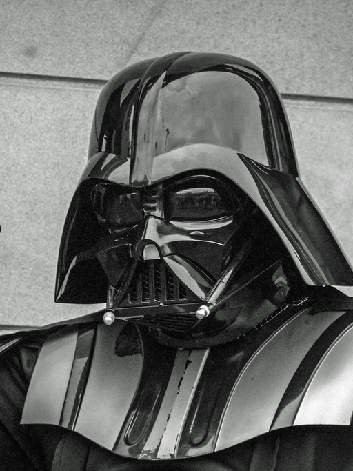 "I am your father" (Darth Vader, Star Wars). Ein Mann in voller Rüstung hebt den rechten Arm, die Hand zur Faust geballt und schaut böse in die Kamera.