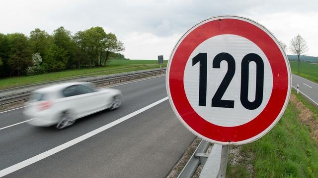Ein Auto fährt auf der Autobahn an einem Tempolimit-Schild (120 k/mh) vorbei. 