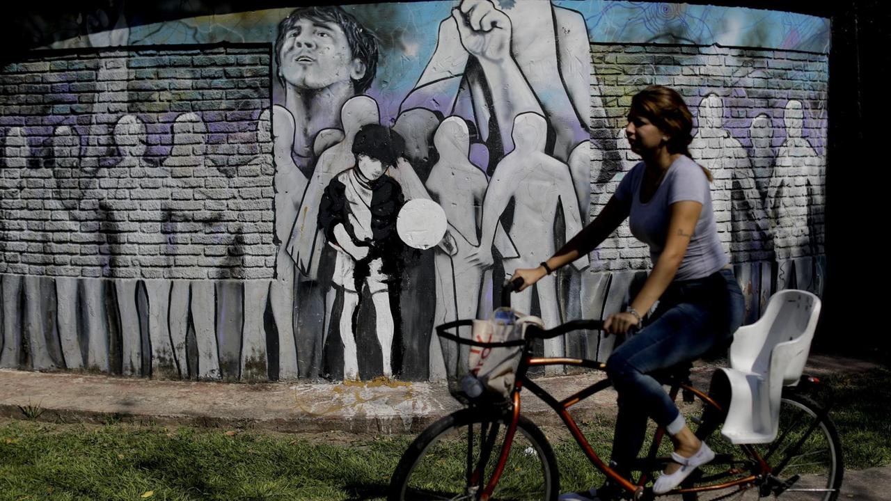 Eine Frau fährt mit dem Fahrrad an der Schule von Fussbalstar Lionel Messi in Rosario in Argentinien vorbei, auf deren Fassade ein Fussball-Mural gemalt wurde, aufgenommen im April 2018.