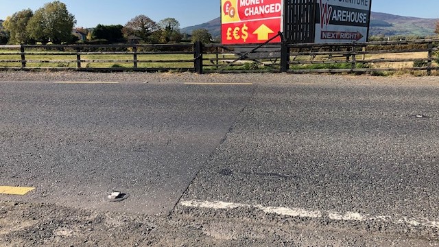 Eine Asphaltstraße in ländlicher Umgebung. In der Mitte wechseln die Markierungen auf der Straße die Farbe. Eine Asphaltstraße in ländlicher Umgebung. In der Mitte wechseln die Markierungen auf der Straße die Farbe.