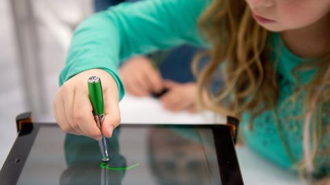 Ein Mädchen arbeitet auf der Bildungsmesse "Didacta" in Stuttgart an einem iPad.