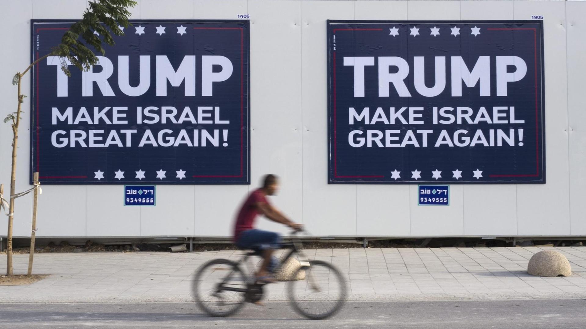 Ein israelischer Radfahrer fährt in Tel Aviv an zwei Plakaten vorbei, auf denen steht: "Trump - Make Israel Great Again". Ein israelischer Radfahrer fährt in Tel Aviv an zwei Plakaten vorbei, auf denen steht: "Trump - Make Israel Great Again".