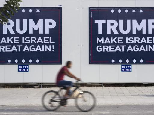 Ein israelischer Radfahrer fährt in Tel Aviv an zwei Plakaten vorbei, auf denen steht: "Trump - Make Israel Great Again".