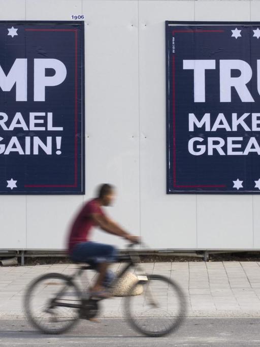 Ein israelischer Radfahrer fährt in Tel Aviv an zwei Plakaten vorbei, auf denen steht: "Trump - Make Israel Great Again".