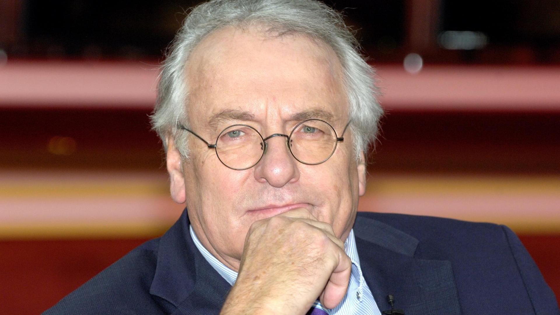 Ein Mann in mittleren Jahren schaut grübelnd, das Kinn in die Hand gestützt, in die Kamera. Er ist ein massiger Typ und trägt Jacket und Krawatte. Ein Mann in mittleren Jahren schaut grübelnd, das Kinn in die Hand gestützt, in die Kamera. Er ist ein massiger Typ und trägt Jacket und Krawatte.