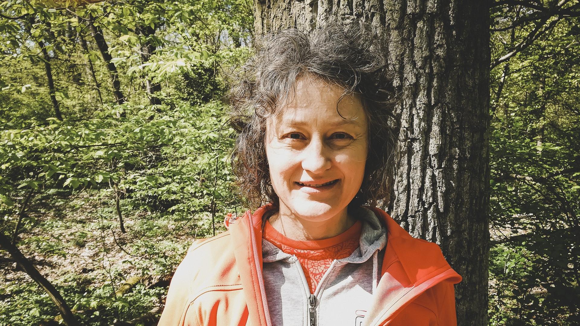 Private Aufnahme von Birgit Saalfrank. Sie steht in Funktionskleidung vor einem Baum inmitten eines Waldes. Private Aufnahme von Birgit Saalfrank. Sie steht in Funktionskleidung vor einem Baum inmitten eines Waldes.