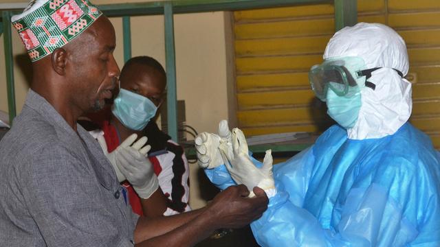 Zwei Gesundheitspfleger ziehen ihre Schutzauszüge aus, nachdem sie ihre Schicht zur Behandlung von Ebola-Erkrankten in einem Krankenhaus in Guinea beendet haben.