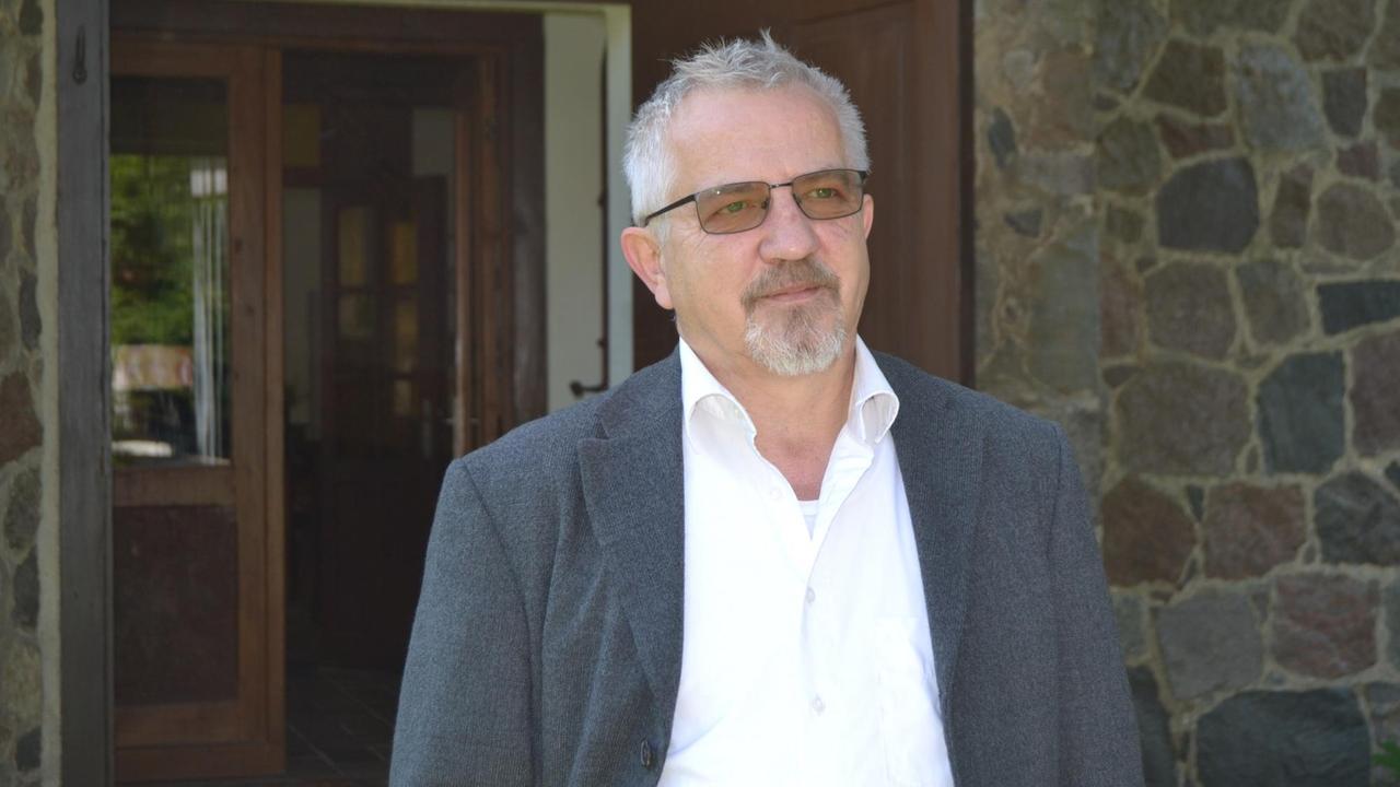 Der Pfarrer Mathias Wolf steht vor einer Kirche in Stechlin. Der Pfarrer Mathias Wolf steht vor einer Kirche in Stechlin.