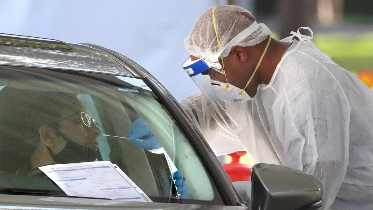 Ein Mann macht einen Coronatest durch ein Autofenster. Ein Mann macht einen Coronatest durch ein Autofenster.
