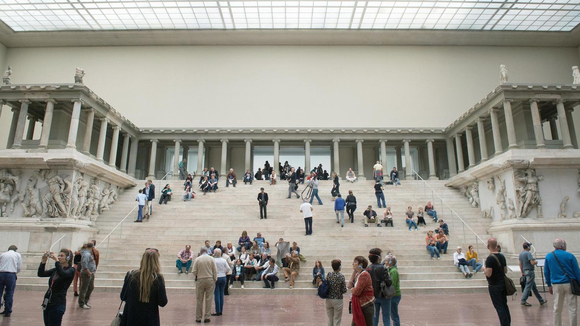 Ansicht des Pergamonaltars im Pergamonmuseum in Berlin. Auf den Stufen sitzen und stehen Museumsbesucher.