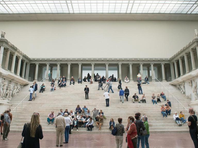 Ansicht des Pergamonaltars im Pergamonmuseum in Berlin. Auf den Stufen sitzen und stehen Museumsbesucher.