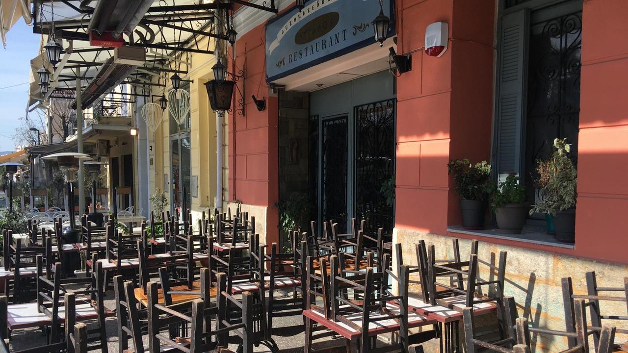 Eine geschlossene Taverne im Athener Ausgehviertel Plaka. Auf den Tischen draußen sind Stühle gestapelt.