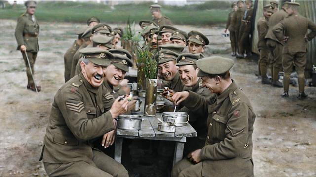 Szene aus dem Dokumentarfilm "They Shall Not Grow Old" von Peter Jackson: lachende Soldaten an einem langen Tisch bei Essen und Bier.