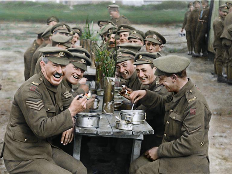 Szene aus dem Dokumentarfilm "They Shall Not Grow Old" von Peter Jackson: lachende Soldaten an einem langen Tisch bei Essen und Bier.