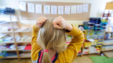 Ein Schulkind steht vor einer an der Wand aufgehängten Zahlenreihe und rauft sich die Haare.