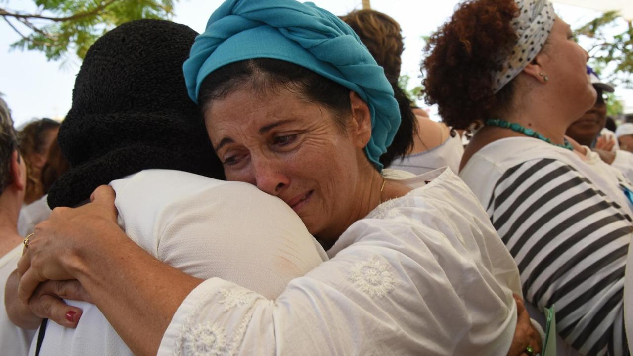 Palästinensische und israelische Frauen der Organisation "Women Wage Peace" umarmen sich während einer Demonstration für den Frieden und ein politisches Abkommen zwischen Israel und Palästinensern (2016, in Qasr al-Yahud, West Bank). Palästinensische und israelische Frauen der Organisation "Women Wage Peace" umarmen sich während einer Demonstration für den Frieden und ein politisches Abkommen zwischen Israel und Palästinensern (2016, in Qasr al-Yahud, West Bank).
